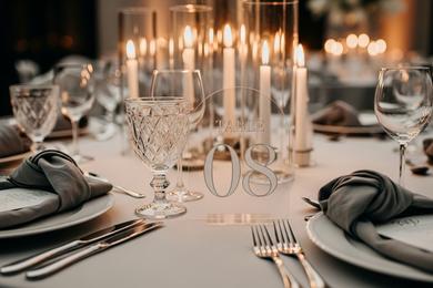A clear acrylic table number with modern white font standing on a rustic wooden table.
