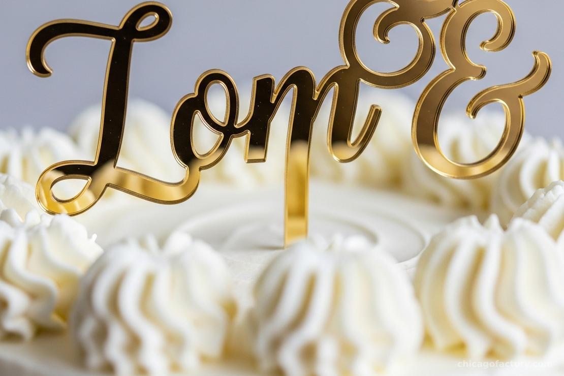 Close-up of a gold mirror acrylic 'Best Day Ever' cake topper on a white buttercream cake.