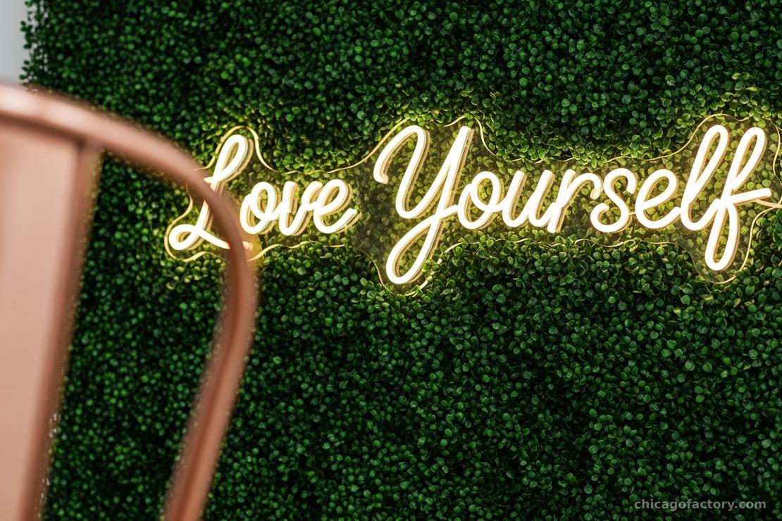 A 'Better Together' style neon sign glowing warmly against a lush greenery wall in an industrial loft.