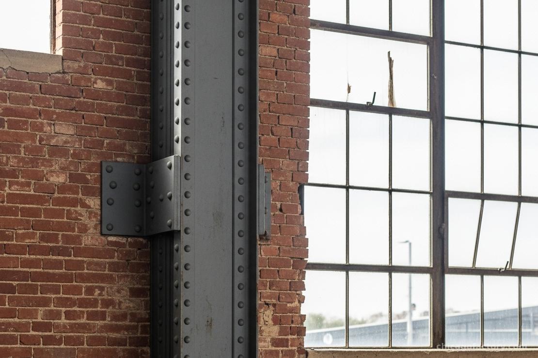 Architectural detail shot showing exposed brick wall meeting steel beam
